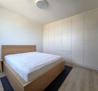 A bright bedroom in a two-room apartment with a large built-in wardrobe and a bed.
