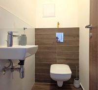 Cozy bathroom with a white sink and toilet, floor with wood decor.