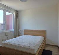 Bedroom in a 2-room apartment with a bed and a large window, floor with wooden decor.
