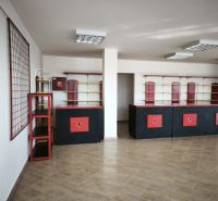 Commercial space with a counter and shelves, wood-patterned flooring, in black and red color.