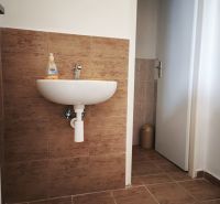 A sink with tile decor in commercial premises with a wooden decor floor.