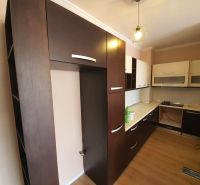 The kitchen in the holiday apartment features dark cabinets and a wooden decor floor.