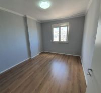 A room in a recreational apartment with a wood-patterned floor and a window.