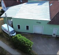 Production premises in Budča with a green facade and a garage door.