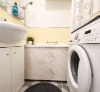 Bathroom with a bathtub, washing machine, and washbasin cabinet in a 3-room apartment.