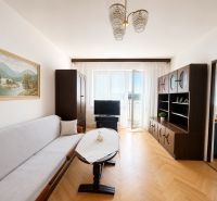 Living room in a 3-room apartment with a wooden decor floor, a sofa, and a built-in wall unit.