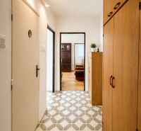 The hallway of a 3-room apartment with tiles and a built-in wardrobe leads to the living room.
