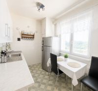 A kitchen in a 3-room apartment with white cabinets and a dining table.