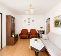Living room with wood-patterned flooring, furniture, and paintings in a 3-room apartment.