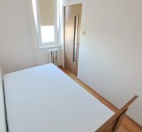 A bedroom with white walls and a wooden decor floor in a 2-room apartment.