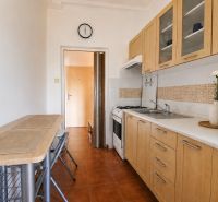 A kitchen in a 2-room apartment with wooden cabinets and a microwave.