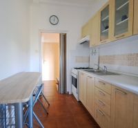 A kitchen in a 2-room apartment with a dining table and appliances.