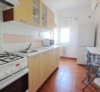 Kitchen in a 2-room apartment with a gas stove, sink, and dining table with chairs.
