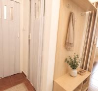 A hallway in a 2-room apartment with built-in wooden storage space and curtains.