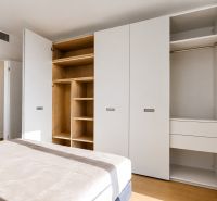 White built-in wardrobe with drawers and open shelves in a 3-room apartment, floor with wood decor.
