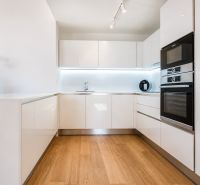 A kitchen in a 3-room apartment with white cabinets and a wooden-patterned floor.