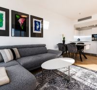 Living room in a 3-room apartment with a comfortable sofa, decorative paintings, and light furnishings.
