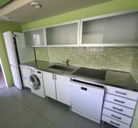 A kitchen in a 3-room apartment with white cabinets and green tiles.