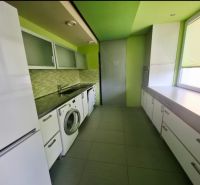 A kitchen in a 3-room apartment with a washing machine, white furniture, and green walls.