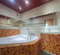 A bathroom with a bathtub tiled with colorful mosaic tiles in a 3-room apartment.