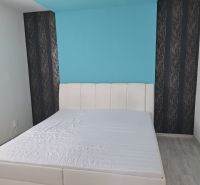 A bright bedroom with a white bed and a blue wall in a 3-room apartment.
