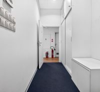 A corridor with white walls and a wooden decor floor in commercial premises.