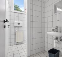 A restroom with white tiles and a sink in commercial premises.