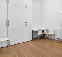 White cabinets, chairs, and a table on a wooden decor floor in commercial premises.