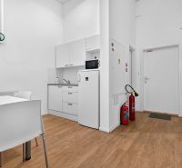 White kitchenette with wood-patterned flooring in commercial premises.