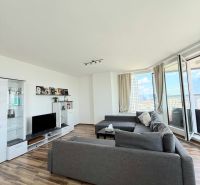 Living room with wood-patterned flooring, a sofa, and a television in a three-room apartment.