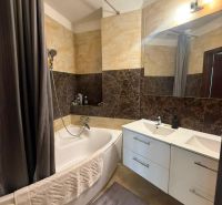 A bathroom with a bathtub, sink, and elegant tiles in a 3-room apartment.