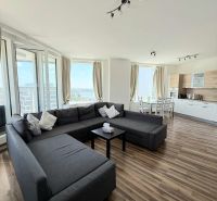 Living room with a large sofa, dining table, and floor with wooden decor.