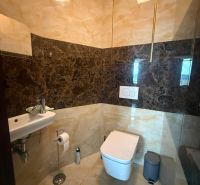 A toilet with a sink in a 3-room apartment, stone cladding and flooring.