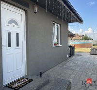 The family house on SNP Street in Čaňa has a gray facade and a landscaped garden with a swimming pool.