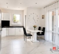 A kitchen in a family house with white furniture and decorative clocks on the wall.