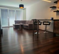 Living room of a two-room apartment with a wooden decor floor and a comfortable sofa set.