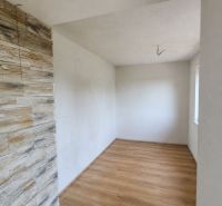 A room in a family house with a wooden decor floor and stone cladding on the wall.