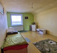 A simple room with a bed, light-colored walls, and a floor with a wooden decor.