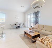 A bright living room in a three-room apartment with a comfortable sofa and a dining table.