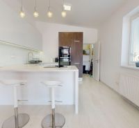 A kitchen in a 3-room apartment with an island, bar stools, and white cabinets.
