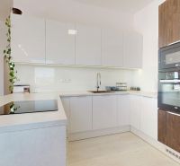 A kitchen with white cabinets, built-in appliances, and a wooden decor floor in a 3-room apartment.