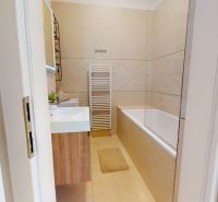 Bathroom with a bathtub and radiator in a 3-room apartment, white and beige design.
