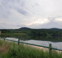A lake surrounded by greenery and forests, reflecting nature in a quiet and picturesque setting.