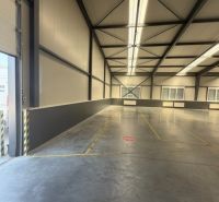 Interior of a warehouse hall with a concrete floor and steel structure.