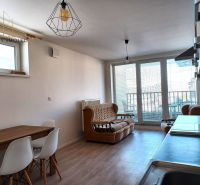 Living room in a two-room apartment with a couch, table, and large windows to the terrace.