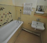 A bathroom in a 2-room apartment with a bathtub and sea wall decoration.