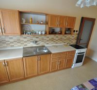 A kitchen with wooden cabinets and mosaic tiles in a 2-room apartment.