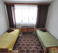 A bedroom with two single beds, a carpet, and a window in a 2-room apartment.