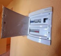 An electrical distribution box with open doors in the interior of a family house.