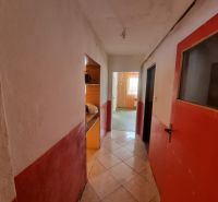 A hallway in a family house with a tiled floor and red doors.